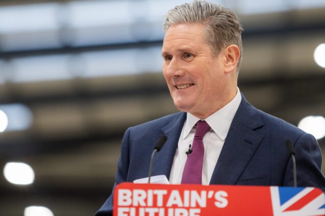 Keir Starmer smiling behind a podium that says 'Britain's Future' on it