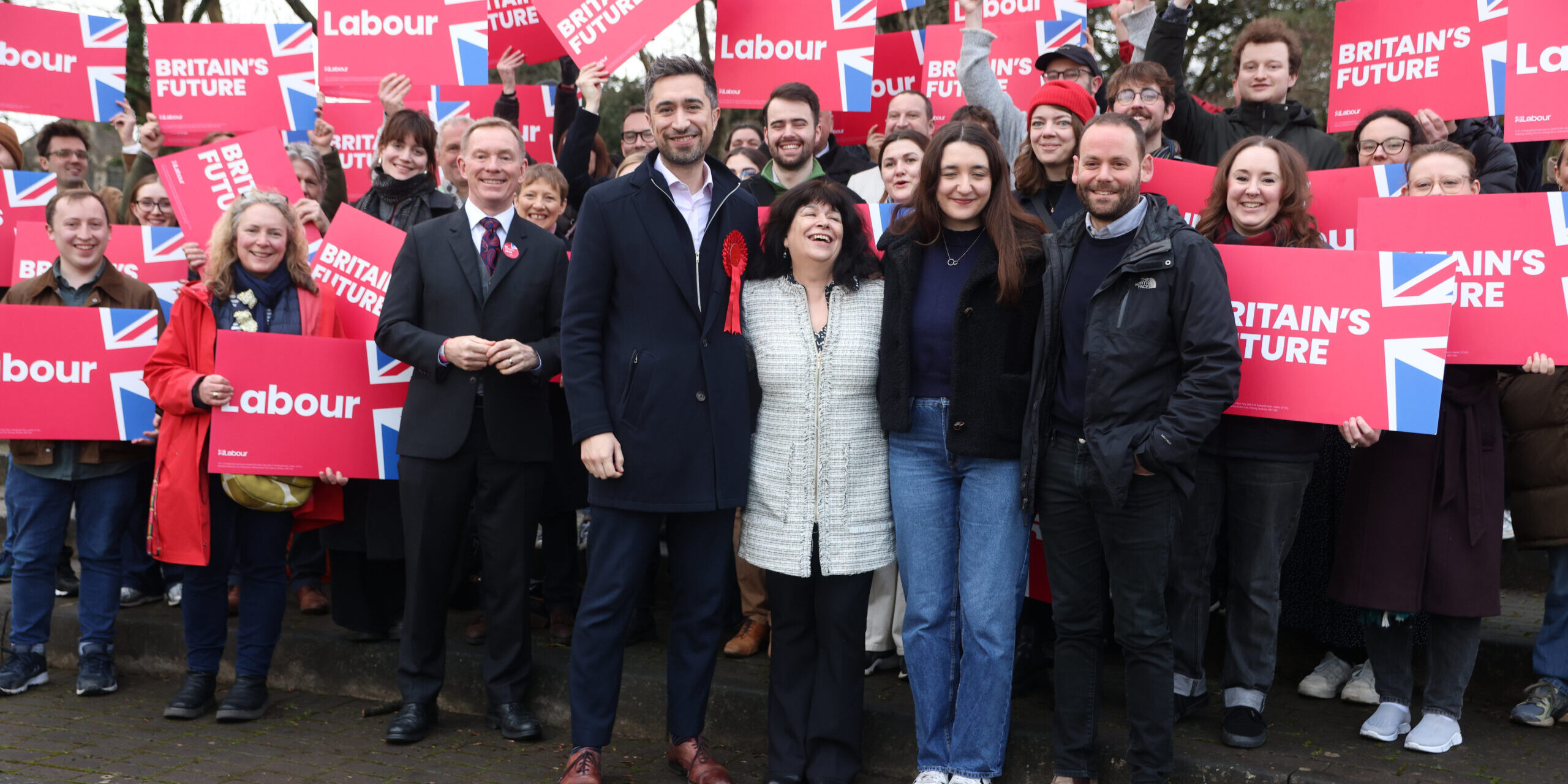 New Labour MP Damien Egan surrounded by supporters waving red Labour placards