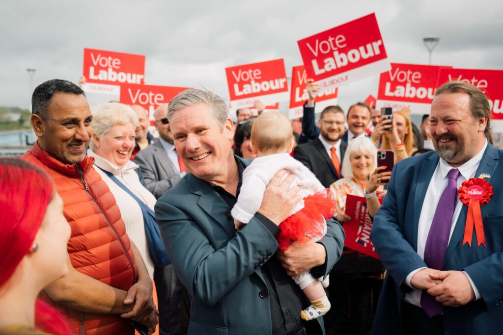 Keir Starmer holds a baby among a crowd of Labour supporters