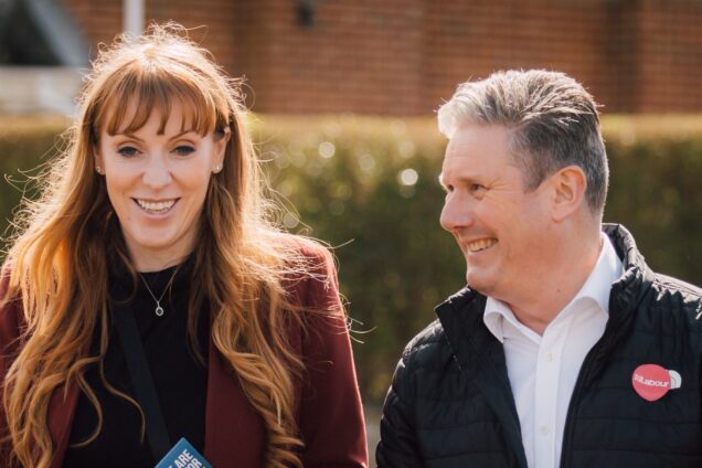 Angela Rayner and Keir Starmer walking along a suburban street with hedgerow behind them