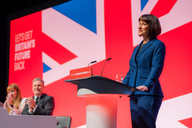 Rachel Reeves at a podium in front of a UK flag