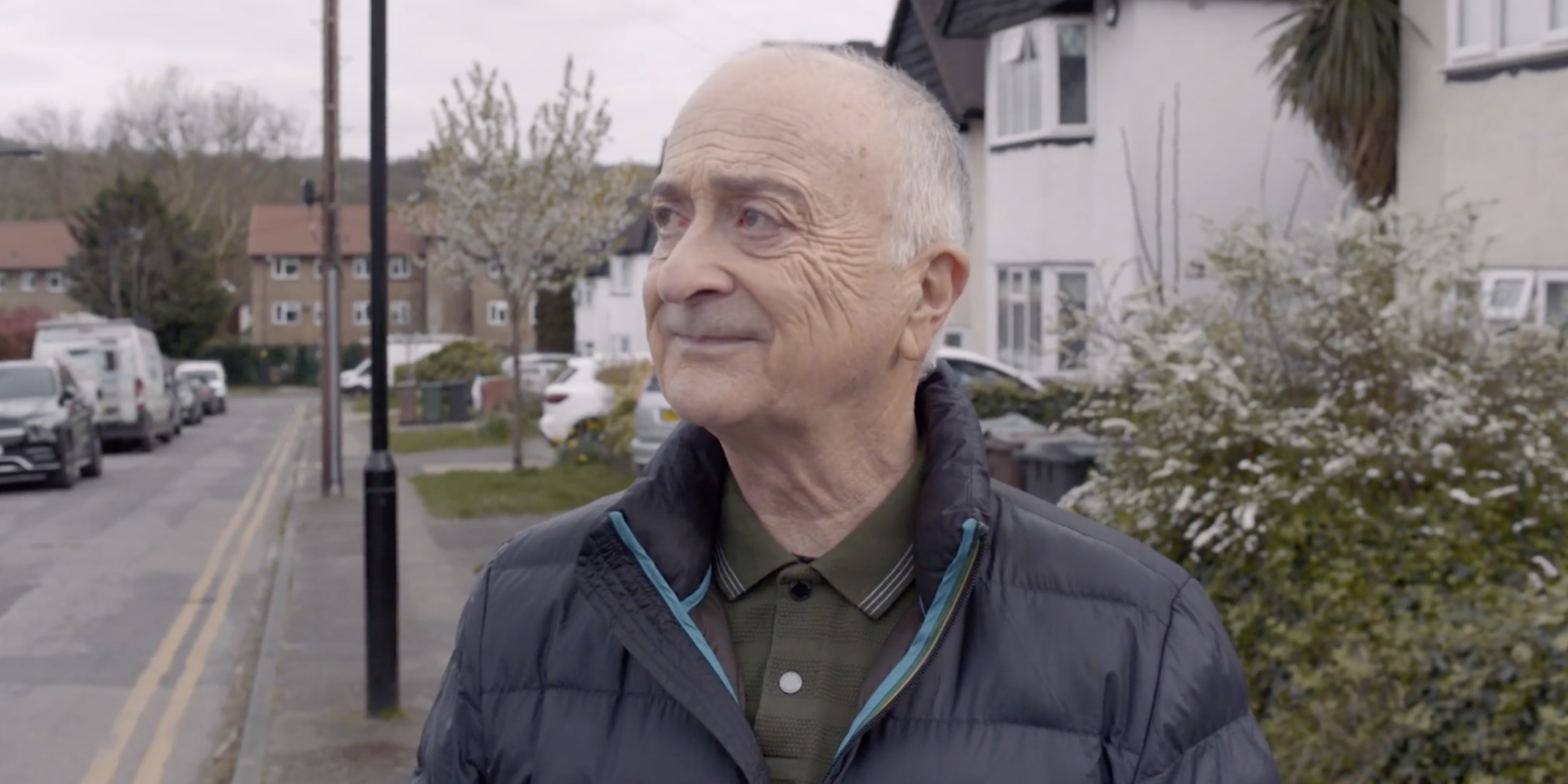 Tony Robinson looks out to the right while standing on a residential street