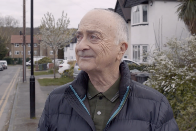 Tony Robinson looks out to the right while standing on a residential street