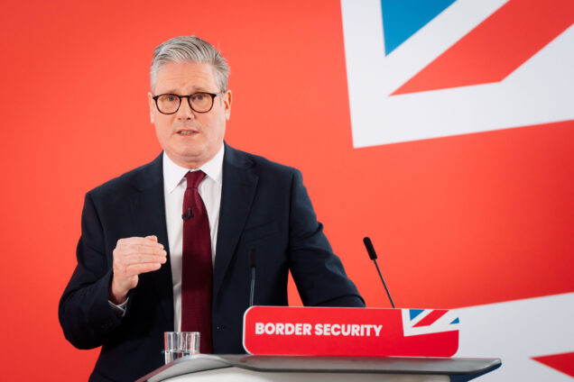 Keir Starmer standing at a podium in front of a Union Jack backdrop. The podium says 'Border security' on it