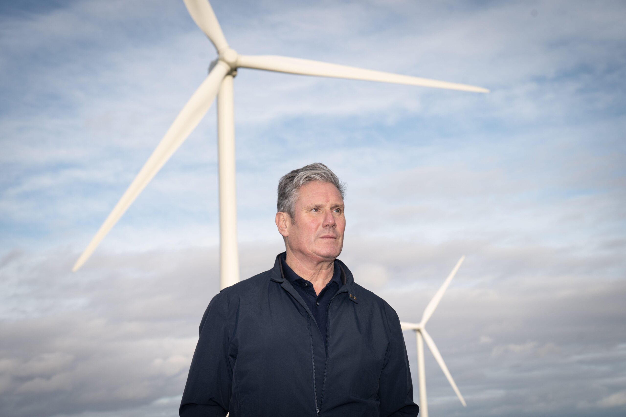 Keir Starmer stands in front of some wind turbines at an on-shore wind farm near Grimsby.