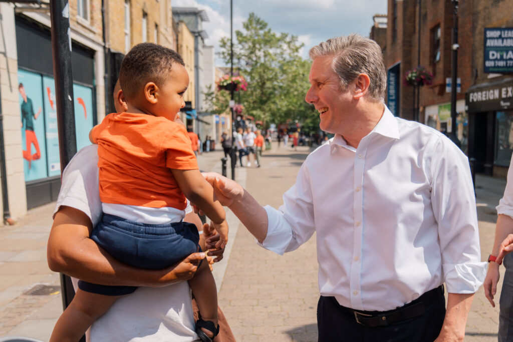 Keir Starmer greeting a father and his small son in a high street.