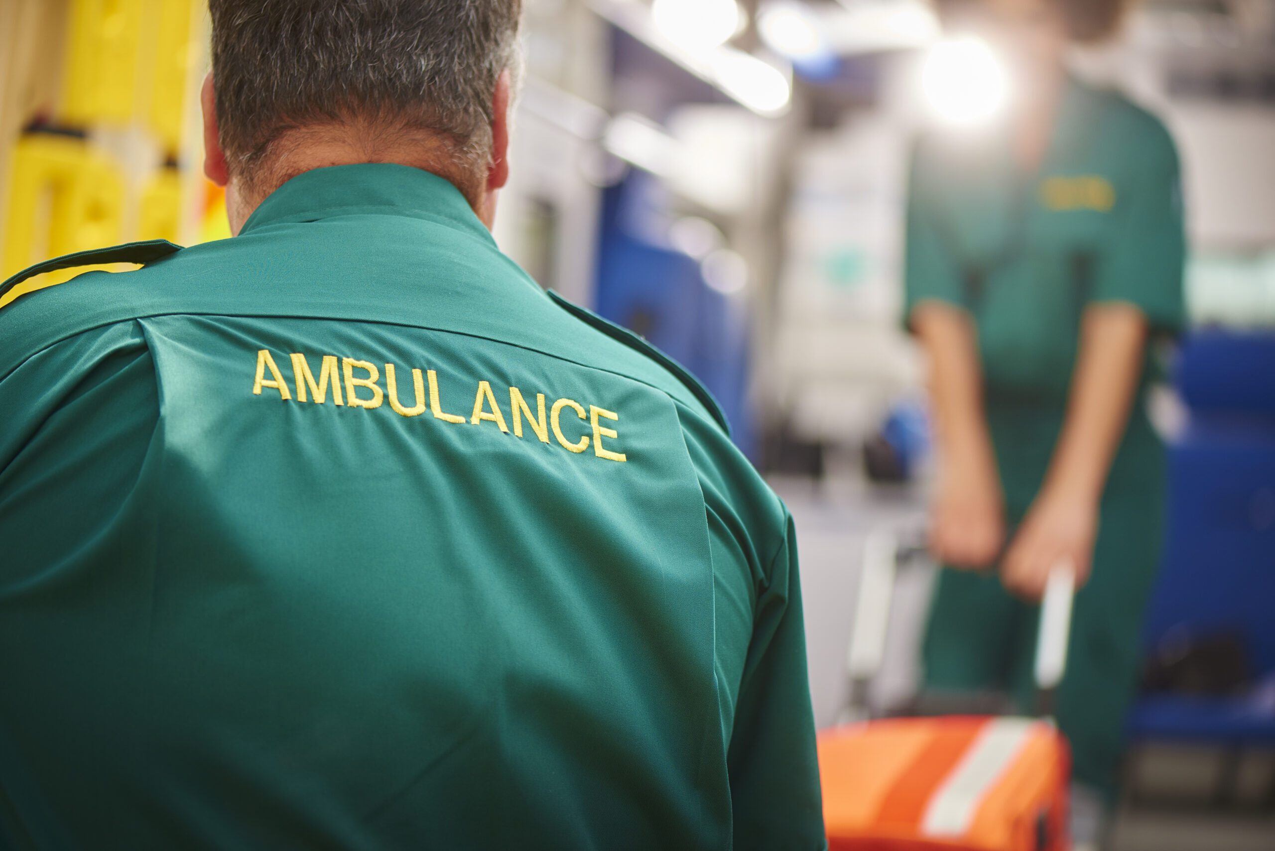 Two ambulance staff members pulling a stretcher on an ambulance.