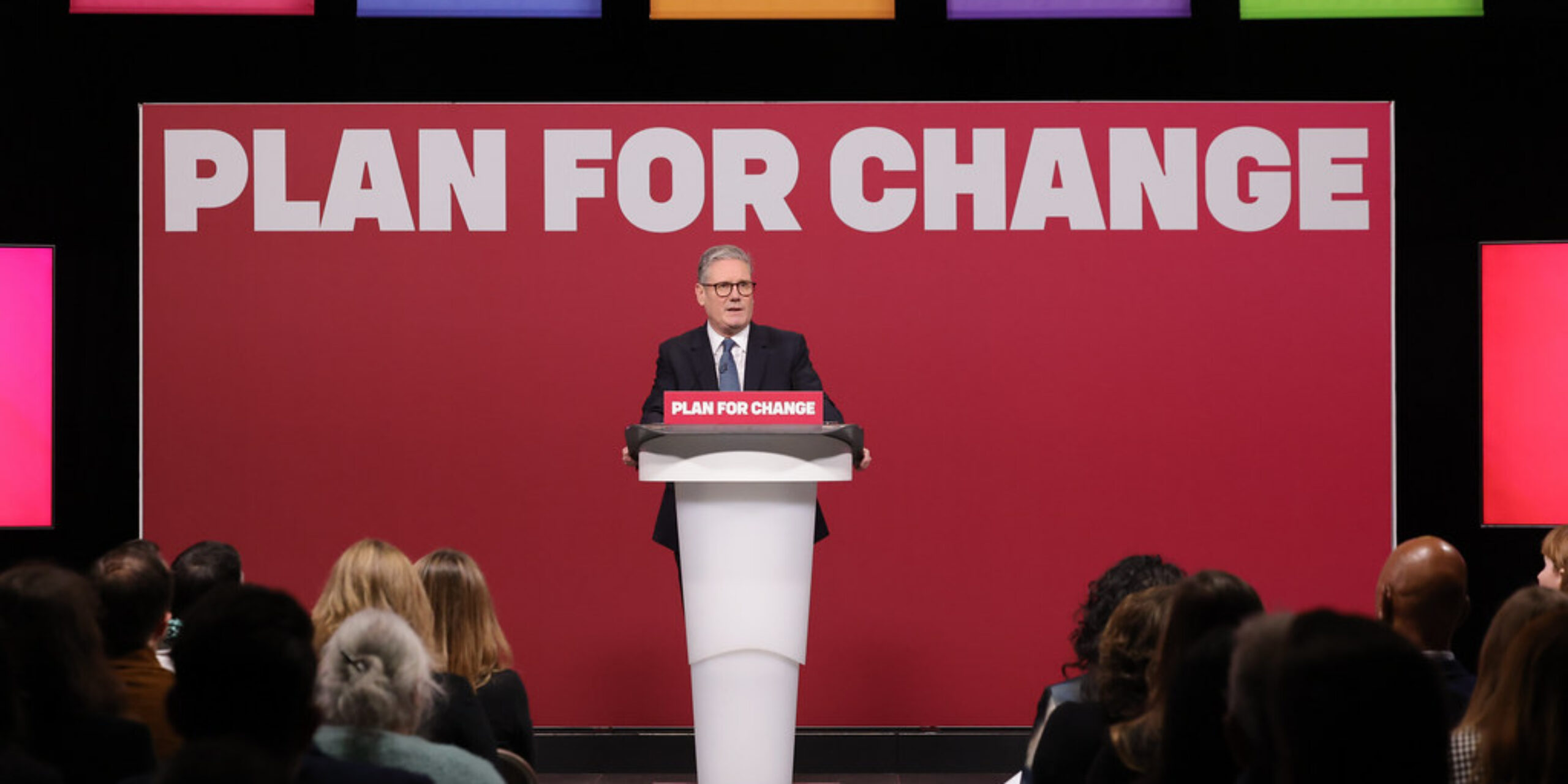 Keir Starmer stood at a podium in front of a slogan reading 'Plan for Change'