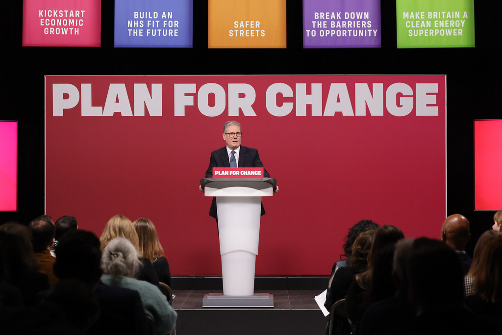 Keir Starmer stood at a podium in front of a slogan reading 'Plan for Change'