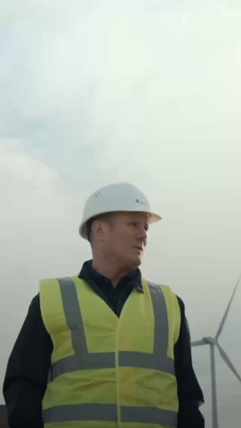 Prime Minister Keir Starmer wearing a hard hat and a hi-vis yellow vest.