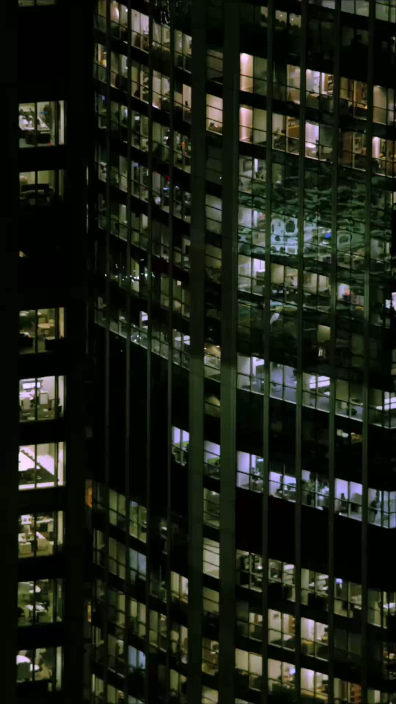 A photo of the outside of an office building in a city at night