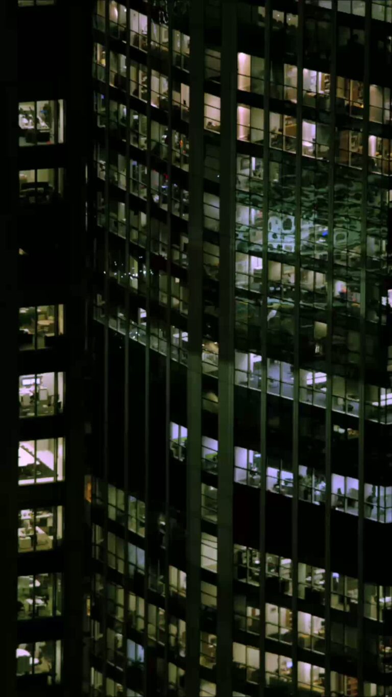 A photo of the outside of an office building in a city at night