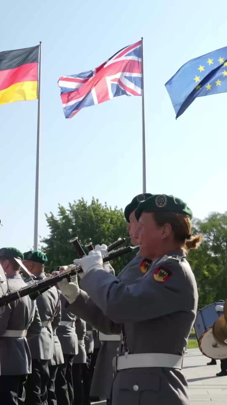 A German Army band playing music in front of German, British and EU flags