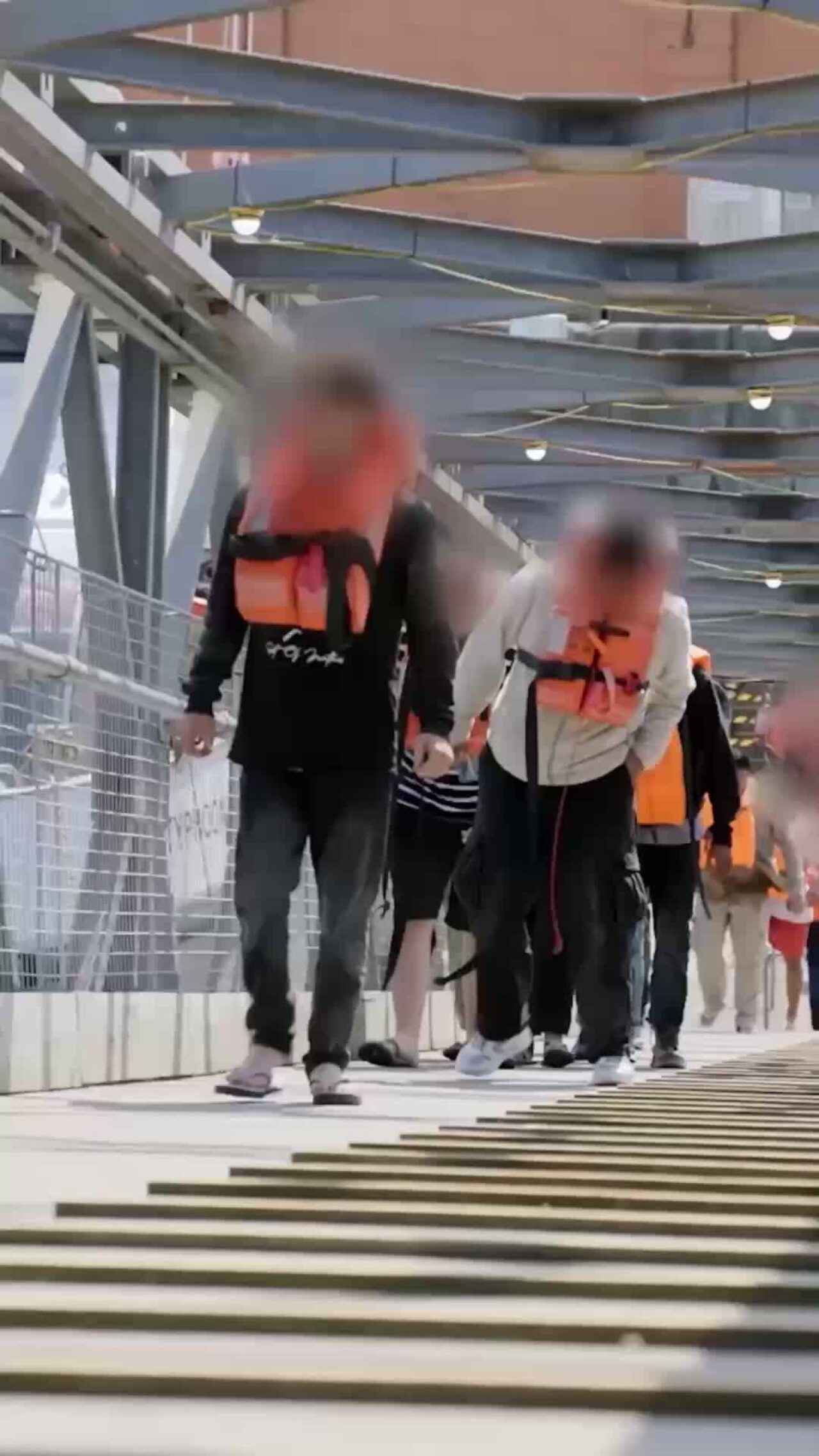 People in life jackets walking along a gangway or a walkway